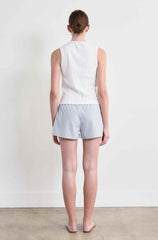 Person wearing a white sleeveless top and light gray shorts against a plain white background