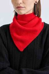 Person wearing a black sweater with a red knitted scarf against a light gray background